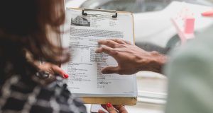 Real estate agent discussing property details with client using a clipboard indoors.
